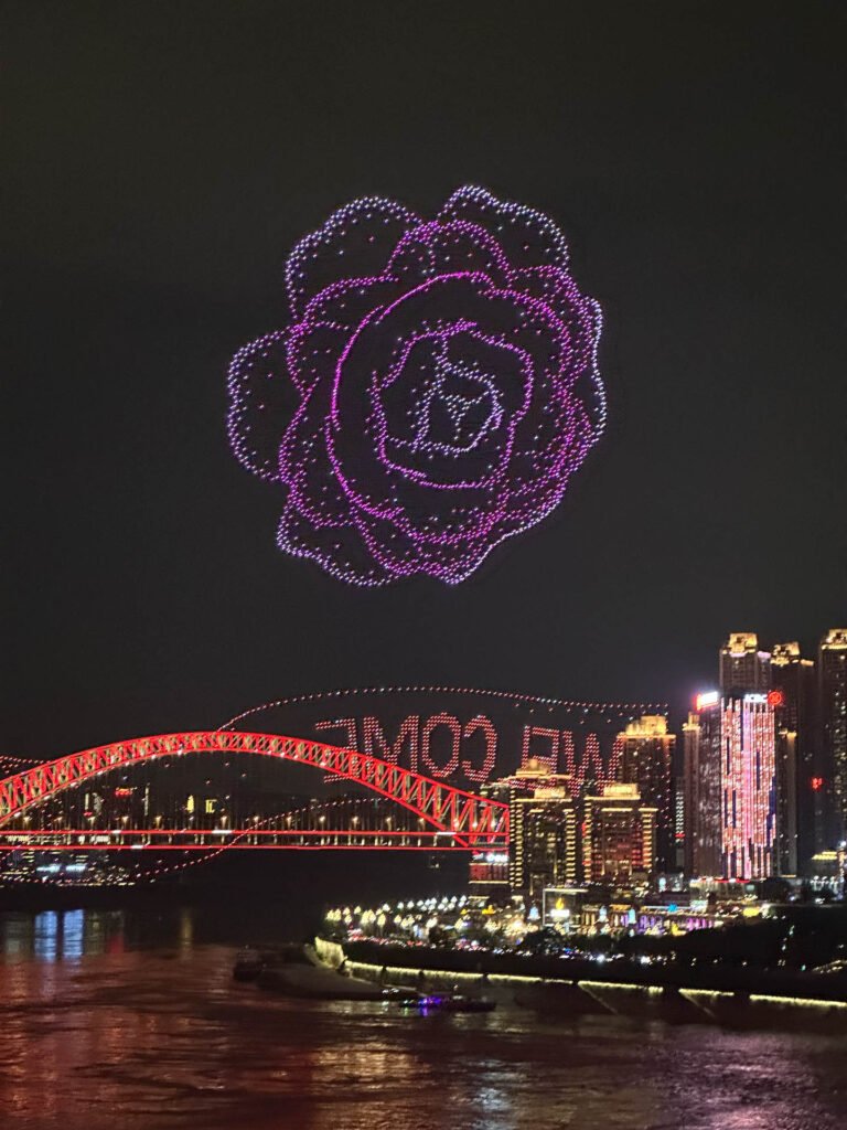 Dramatic floral pattern created by colorful drones illuminates the night sky over Chongqing during our private tour